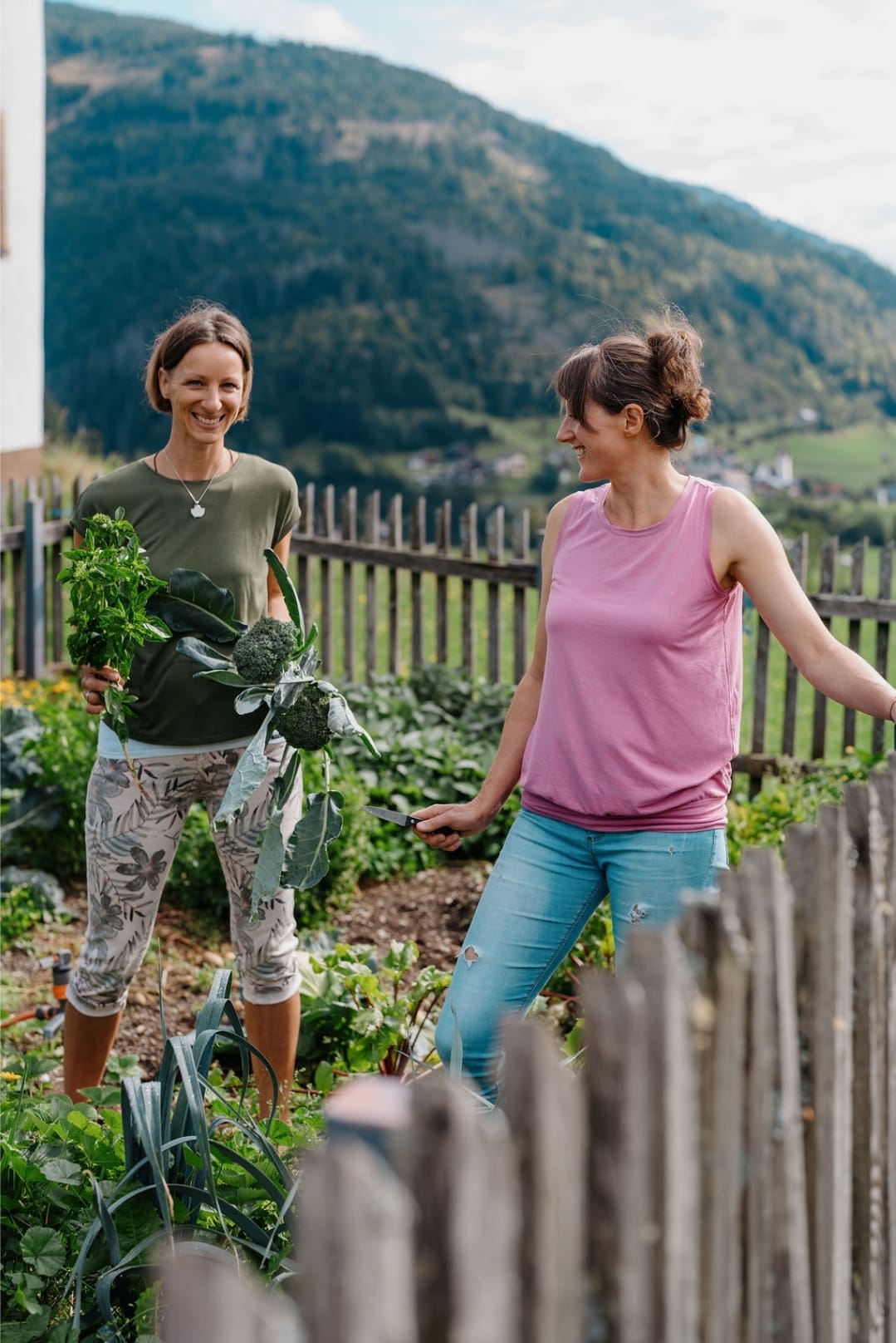 Elisabeth und Sonja im Gemüsegarten mit frisch geerntetem Brokkoli und Kräutern
