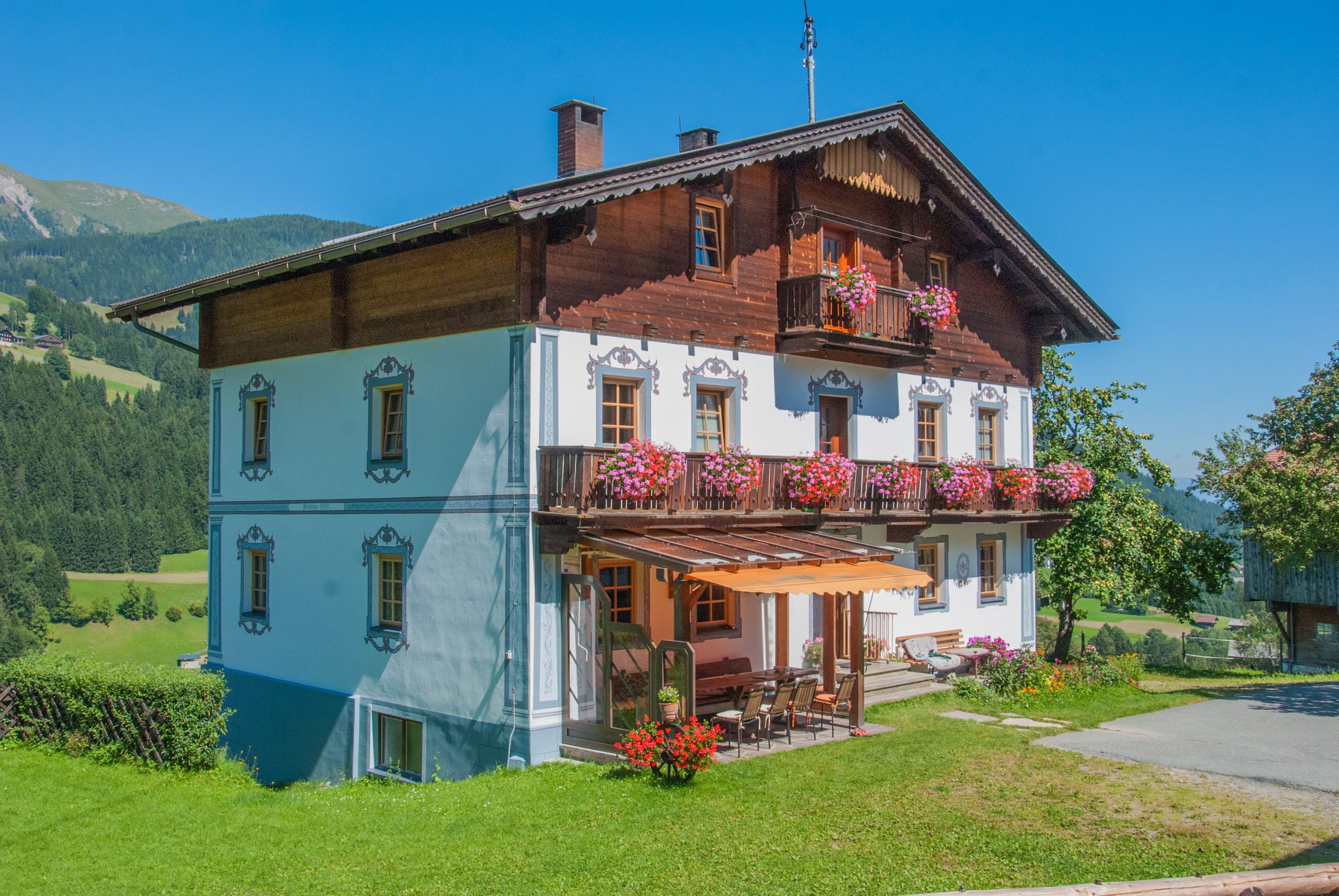 Das Bauernhaus in der Sonne, dahinter die Bergwiesen